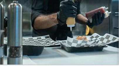 Kitchen cook adding condiments to food